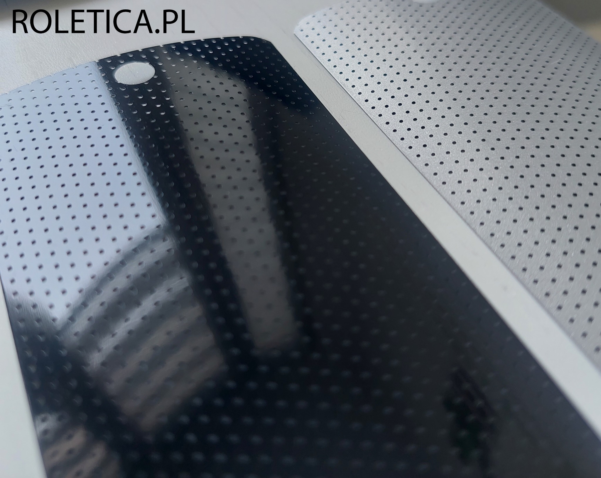 Detale perforowanych lameli aluminiowych w kolorze czarnym i srebrnym, widoczne otwory montażowe, zbliżenie na strukturę materiału.