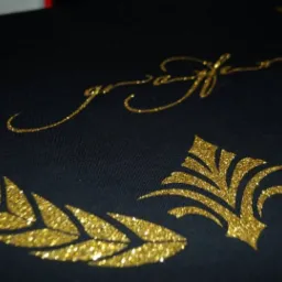 Czarna koszulka z błyszczącym, złotym nadrukiem w kształcie wieńca laurowego i ozdobnego napisu wykonanym w Białymstoku.