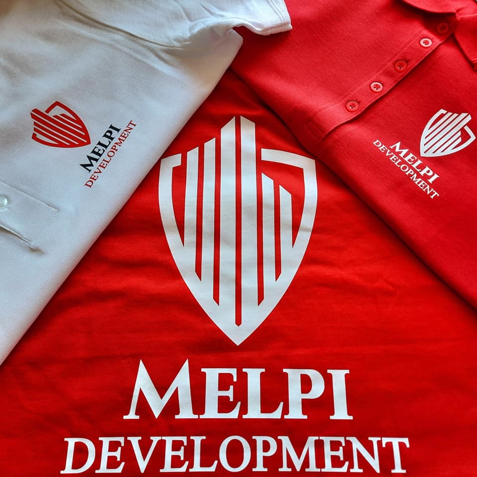 Czerwona i biała koszulka polo z logo i nazwą firmy MELPI DEVELOPMENT, ułożone pod kątem, pokazujące detale nadruku.