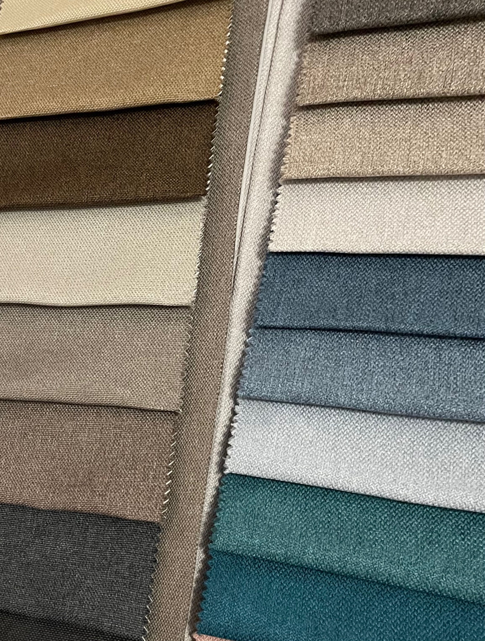 Próbniki tkanin w różnych odcieniach brązu, beżu, szarości i zieleni, prezentowane obok siebie. Widoczna faktura materiałów i krawędzie z delikatnymi przeszyciami.