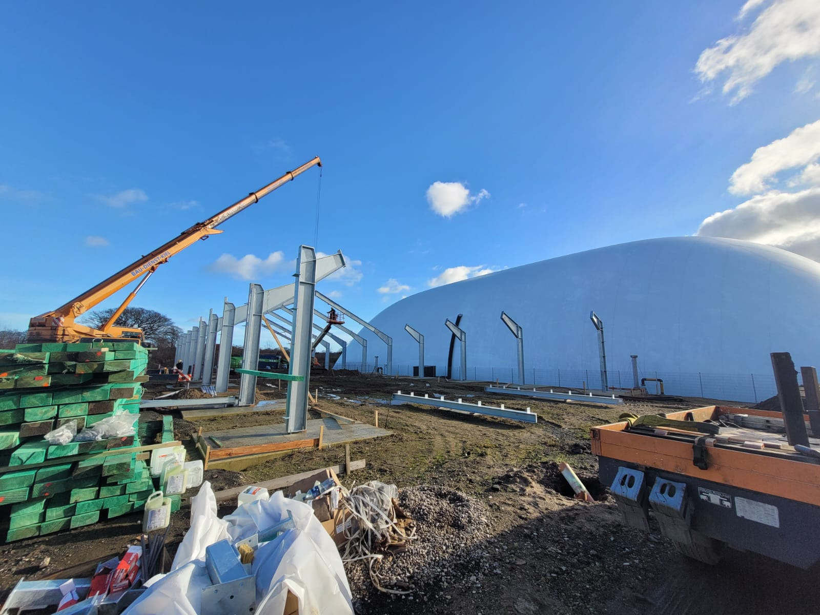 Konstrukcja stalowa hali w trakcie budowy w Szczecinie, widoczny dźwig, elementy konstrukcyjne i kopuła w tle.