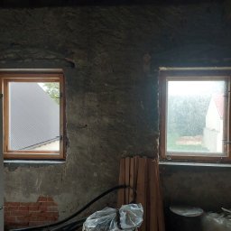 Adrian Filipczyk - Dwa okna w drewnianych ramach, jedno czyste z widokiem na blaszany dach, drugie brudne z widokiem na zieleń, w surowym wnętrzu w Świebodzicach.