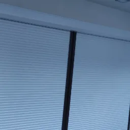 Zamknięte, białe żaluzje fasadowe w nowoczesnym wnętrzu w Woli Paprotni z widocznymi, ciemnymi prowadnicami.