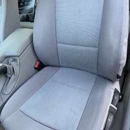 WrapStudio - Mateusz Kędzior - Szare, materiałowe siedzenie samochodowe z widocznym pasem bezpieczeństwa i regulacją. Na zagłówku widoczny czarny worek z instrukcją.