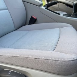 WrapStudio - Mateusz Kędzior - Szare, materiałowe siedzenie samochodowe z widocznym pasem bezpieczeństwa, dźwignią zmiany biegów i elementami regulacji fotela.