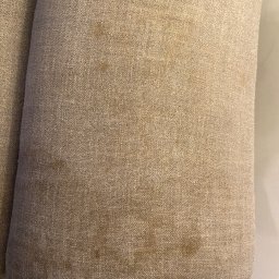 WrapStudio - Mateusz Kędzior - Fragment sofy z beżową tapicerką, widoczne plamy na materiale i wyraźna faktura tkaniny.