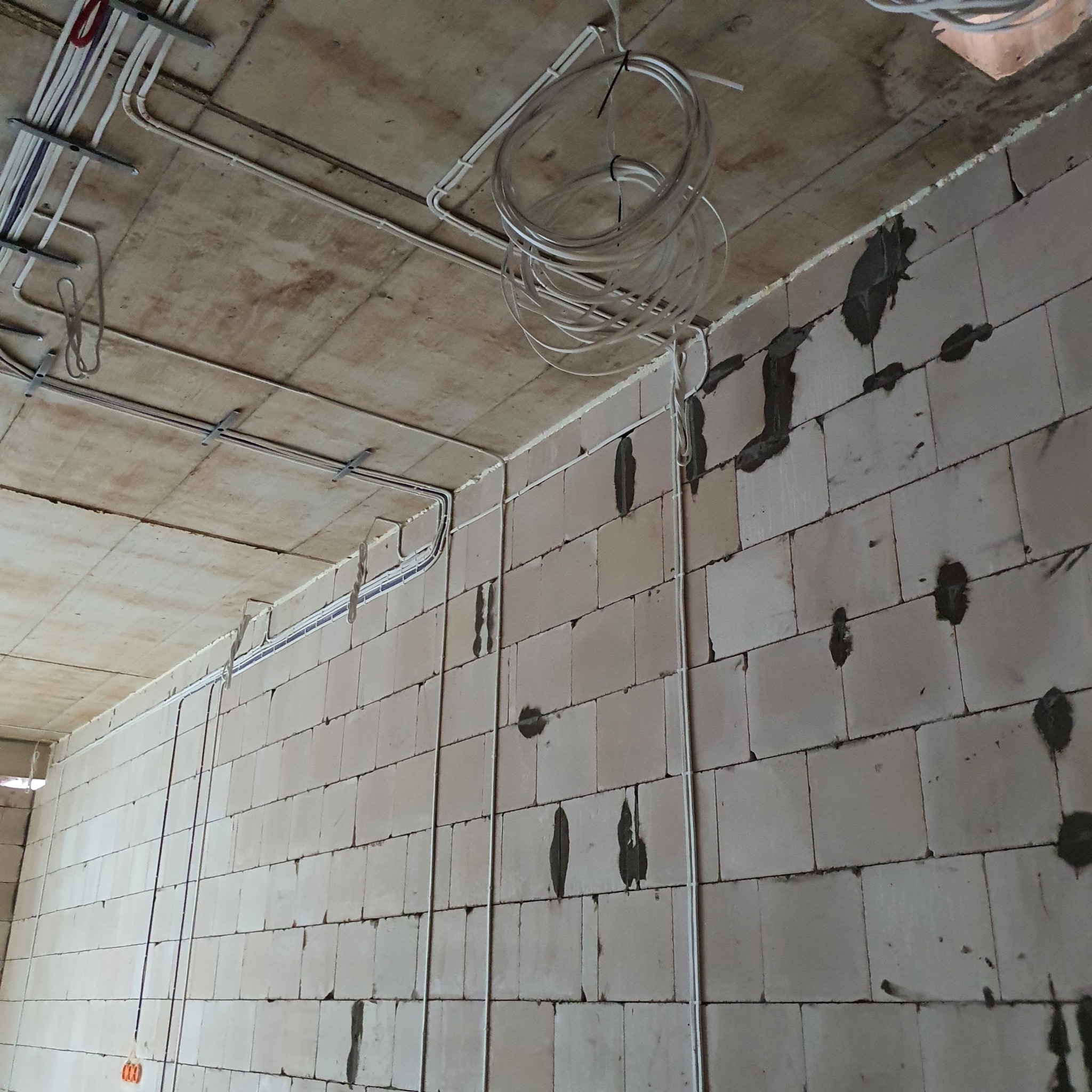 Surowy stan: przewody elektryczne ułożone na suficie i ścianach z betonu komórkowego, przygotowane do tynkowania. Widoczne puszki instalacyjne.
