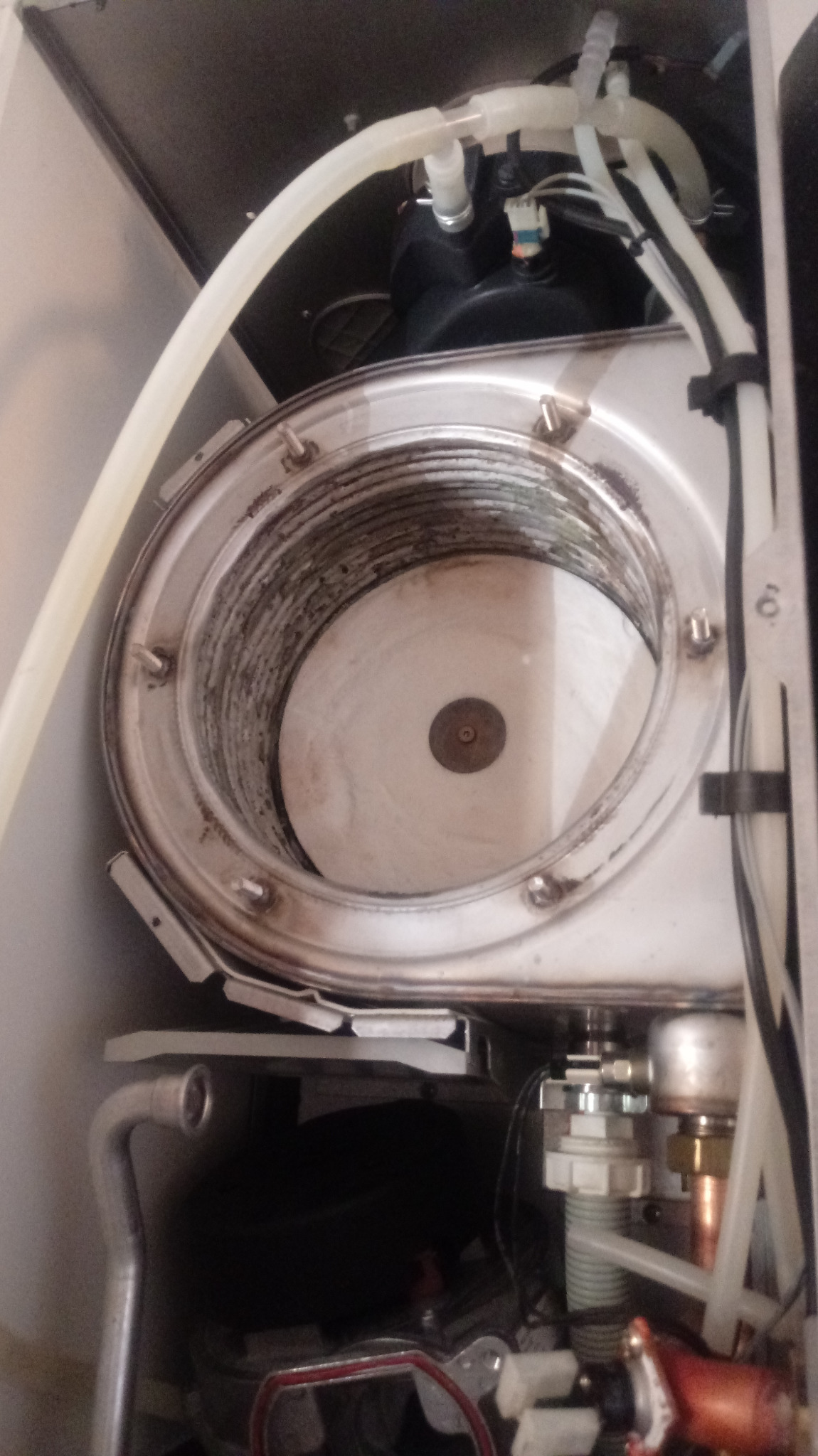 Wnętrze kotła gazowego z widocznym palnikiem i elementami instalacji, widoczne ślady użytkowania i zabrudzenia.