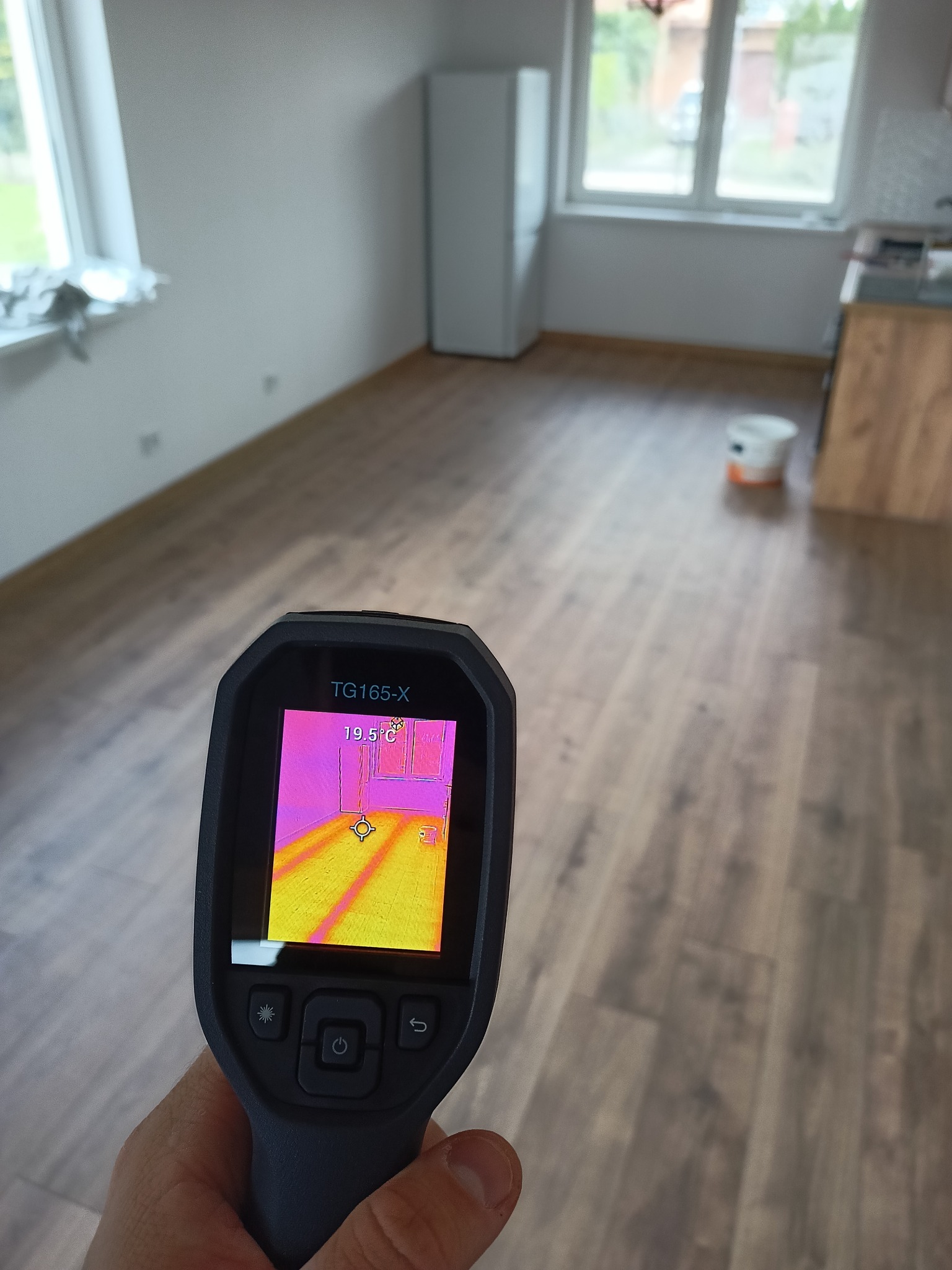 Pomiar temperatury podłogi kamerą termowizyjną TG165-X po instalacji ogrzewania podłogowego w nowym pomieszczeniu z drewnopodobną podłogą.