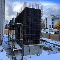 VANBLOK SPÓŁKA Z OGRANICZONĄ ODPOWIEDZIALNOŚCIĄ - Zimowy kadr z budowy hotelu: zbrojenie ścian na fundamencie, rusztowania, śnieg. Widoczne elementy konstrukcyjne i otoczenie placu budowy.