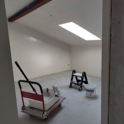 UWAGA!!Wykonanie gładzi,malowanie!i td... - Wnętrze po szpachlowaniu i malowaniu na biało, widoczny wózek z narzędziami malarskimi, drabina i wiadro farby, drewniana belka pod sufitem zabezpieczona taśmą malarską.