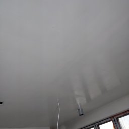 UWAGA!!Wykonanie gładzi,malowanie!i td... - Gładka, świeżo pomalowana na biało powierzchnia sufitu, widoczne okno z folią ochronną i wystający kabel elektryczny.