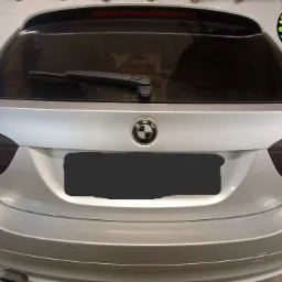 Srebrne BMW kombi z przyciemnionymi tylnymi szybami i lampami, widoczne logo firmy oklejającej samochody w prawym górnym rogu.