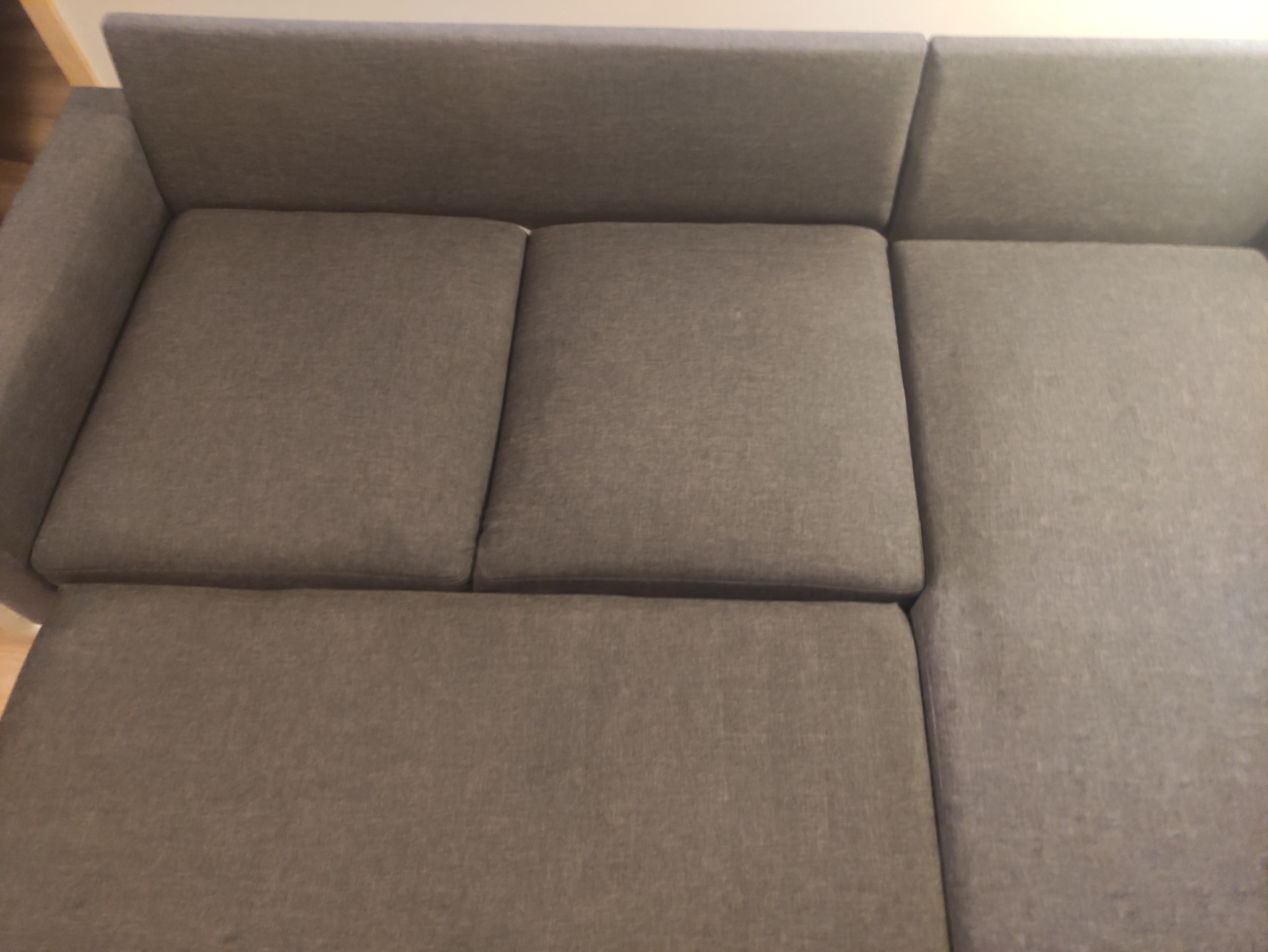 Szary narożnik z wysuwanym siedziskiem, widok z góry, prezentujący fakturę tkaniny obiciowej.