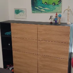 Szafa na wymiar z drewnianymi frontami, czarnym korpusem i otwartą półką boczną, udekorowana obrazami dziecięcymi i figurkami.