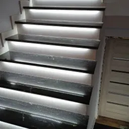 Schody z czarnego kamienia z podświetleniem LED zamontowanym pod każdym stopniem, widoczne z boku.