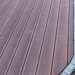 B&B Gw Sp Zoo - Brązowa deska tarasowa ułożona pod kątem, obrzeże z szarych kostek brukowych, widok z góry.