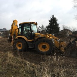 B&B Gw Sp Zoo - Żółta koparko-ładowarka JCB 4CX podczas prac ziemnych na działce budowlanej, widoczne budynki mieszkalne w tle.