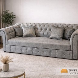 Zakład Usługowy Tapicerstwo Meblowe Jacek Sęków - Elegancka, szara sofa Chesterfield z poduszkami w salonie. Pikowane oparcie i siedzisko, dekoracyjne guziki. Widoczny stolik kawowy i lampka nocna.