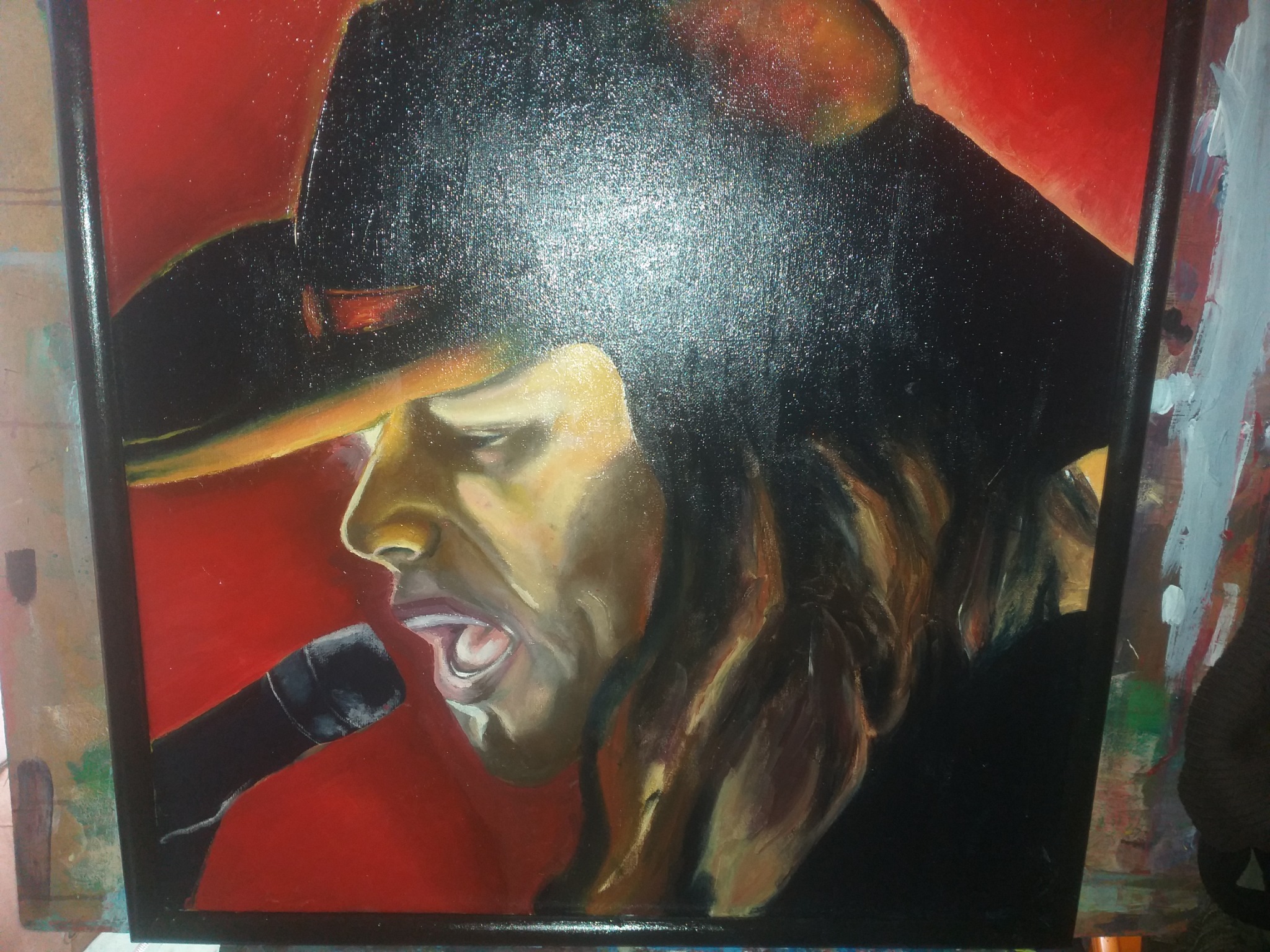 Portret wokalisty w kapeluszu, namalowany farbami olejnymi na płótnie z czerwonym tłem, widoczne pociągnięcia pędzla i faktura płótna.