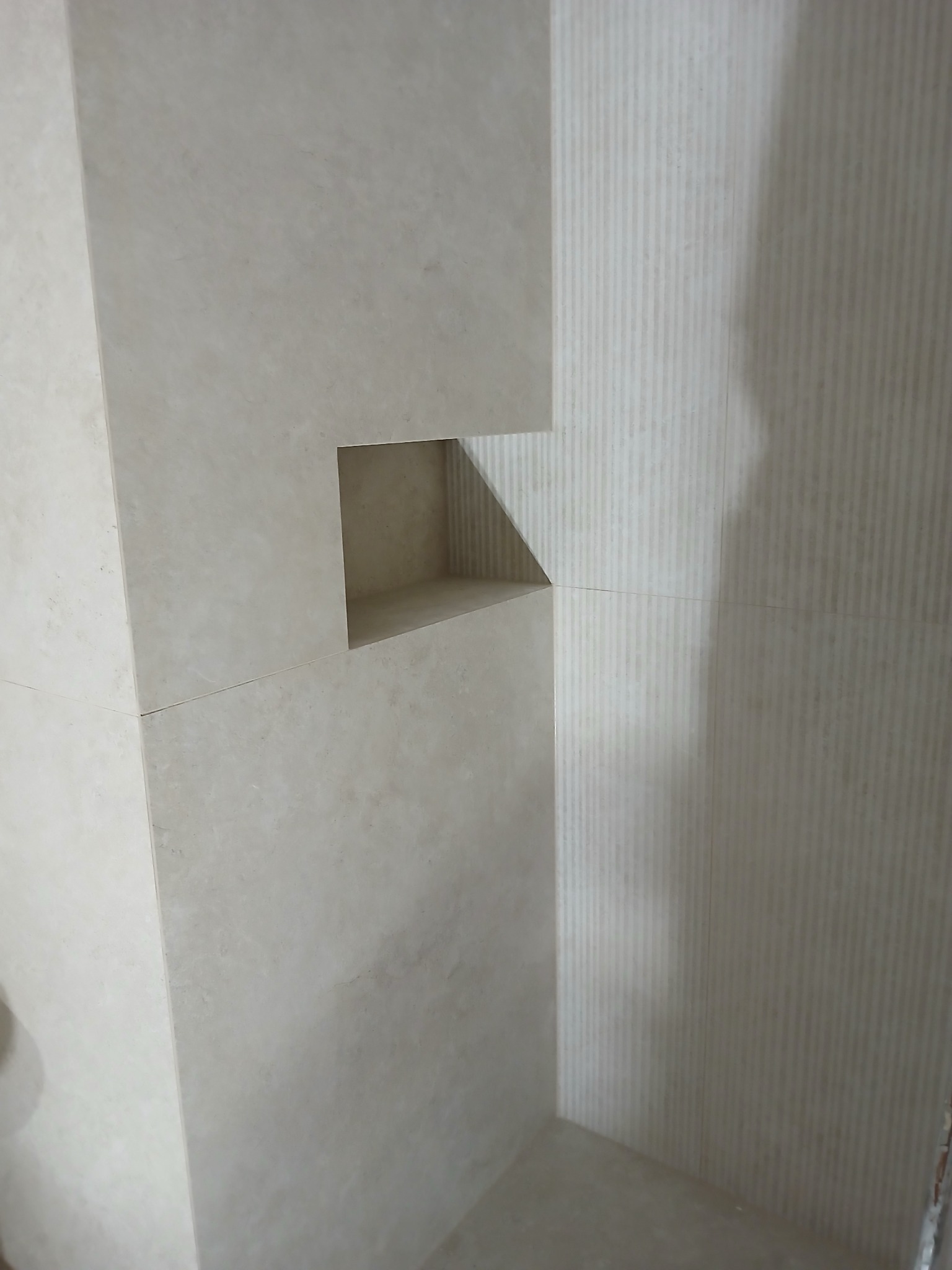 Wykończona wnęka w łazience wyłożonej beżowymi płytkami w Kłobucku. Widoczne pionowe żłobienia na ścianie i precyzyjne łączenia płytek.