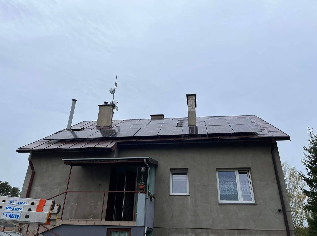 Dom w Milówce z zamontowanymi panelami słonecznymi na dachu, widoczny podnośnik koszowy z boku budynku.