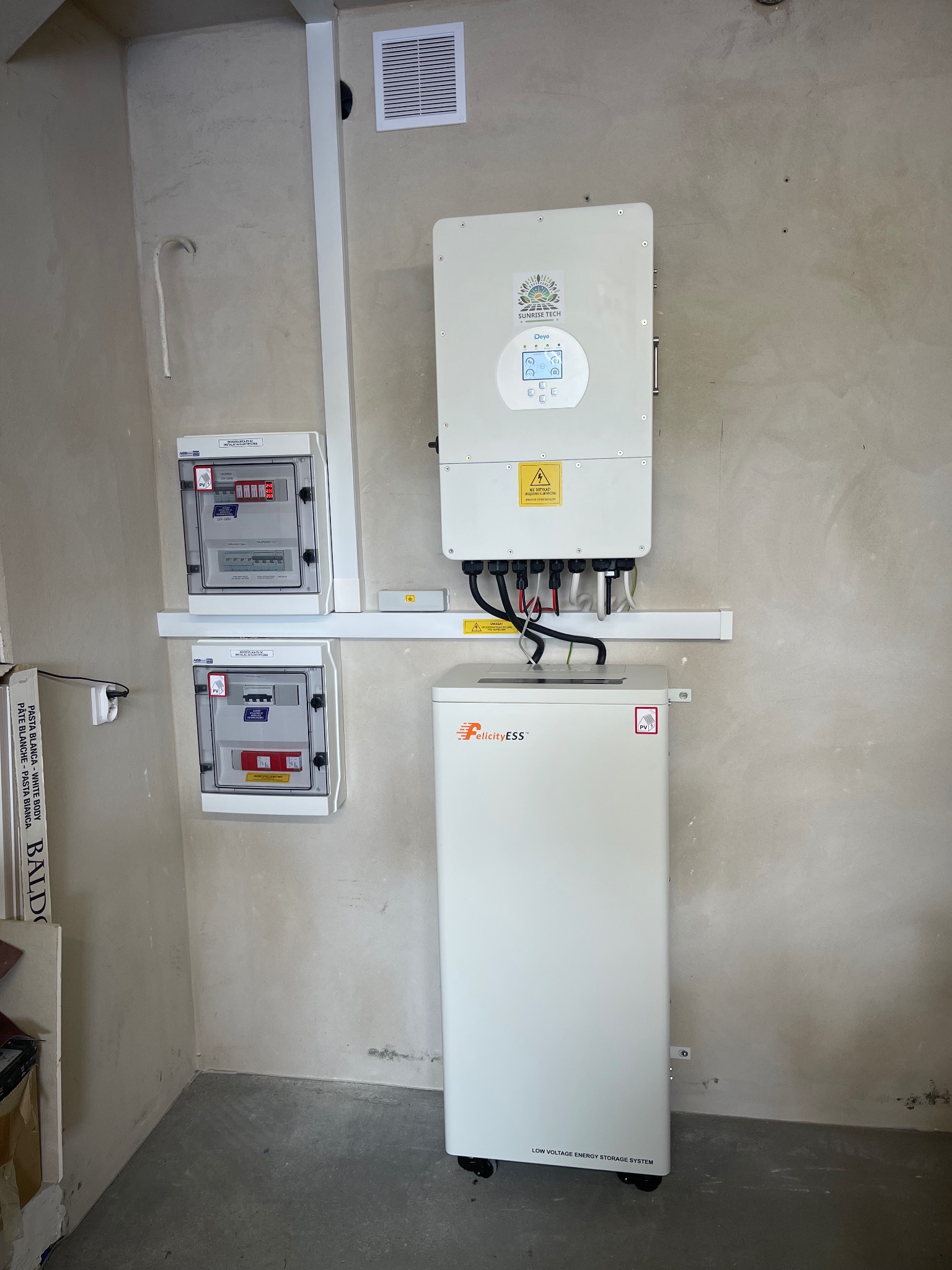 Instalacja magazynu energii FelicityESS i falownika Deye w Milówce, z rozdzielnicami elektrycznymi. Widoczne okablowanie i surowa ściana w tle.