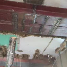 Wzmocnienie stropu stalową konstrukcją, widoczne spawy i oznaczenia na blasze, podparte stemple budowlane.