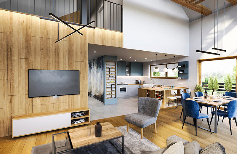 Wnętrze domu z drewnianą ścianą, telewizorem i nowoczesnym oświetleniem, widok na otwartą kuchnię z wyspą i jadalnię z niebieskimi krzesłami.