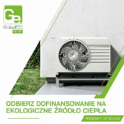 Biała zewnętrzna jednostka pompy ciepła zamontowana na wspornikach przy jasnej ścianie budynku, z widocznym trawnikiem w tle oraz elementami graficznymi reklamy dotacji.