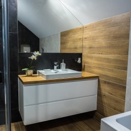Meble Kułakowski Grzegorz Kułakowski - Nowoczesna łazienka w Białymstoku z białą szafką pod umywalkę z drewnianym blatem, drewnopodobnymi płytkami na ścianie i podłodze oraz lustrem na ścianie.