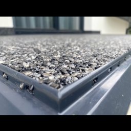 Gab-House Usługi Budowlane Damian Czarnocki - Szczegółowe ujęcie wykończenia dachu z posypką kamienną w odcieniach szarości, z widoczną metalową obróbką krawędzi. Dach w nowoczesnym stylu.