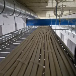 Kable elektryczne ułożone równolegle na perforowanej metalowej korycie kablowej pod sufitem, zabezpieczone opaskami zaciskowymi, widoczne rury wentylacyjne i instalacyjne.