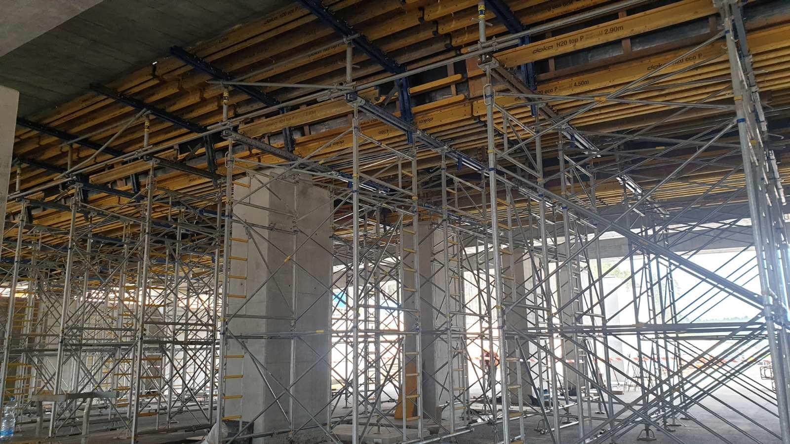 Konstrukcja szalunkowa podtrzymująca strop żelbetowy w trakcie budowy, widoczne metalowe rusztowania i drewniane elementy szalunku.