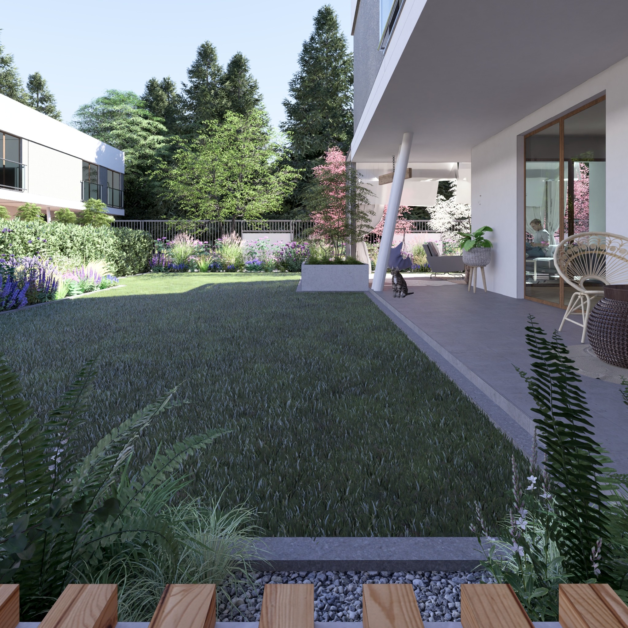 Nowoczesny dom z rozległym trawnikiem, rabatami kwiatowymi i zadaszonym tarasem, na którym siedzi osoba i kot