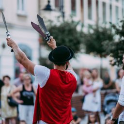 Cyrkowy pokaz uliczny podczas festiwalu w Rzeszowie. Na zdjęciu żonglerka mieczami we dwoje między osobą z publiczności 