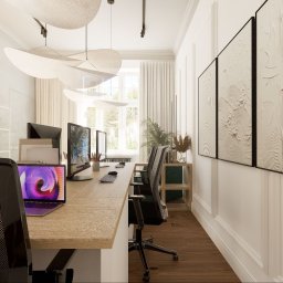 Łukasz Macuga architekt wnętrz - Jasne, nowoczesne biuro z drewnianymi biurkami, komputerami, designerskimi lampami sufitowymi i abstrakcyjnymi obrazami na ścianie.