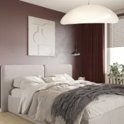 Jasna sypialnia z beżowym łóżkiem, szarym pledem w jodełkę z frędzlami, minimalistycznym obrazem na ścianie i roślinami w doniczkach na parapecie okna z żaluzjami.