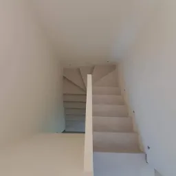 Nowoczesne, minimalistyczne schody w jasnej tonacji, prowadzące w górę, z oświetleniem punktowym na ścianie.