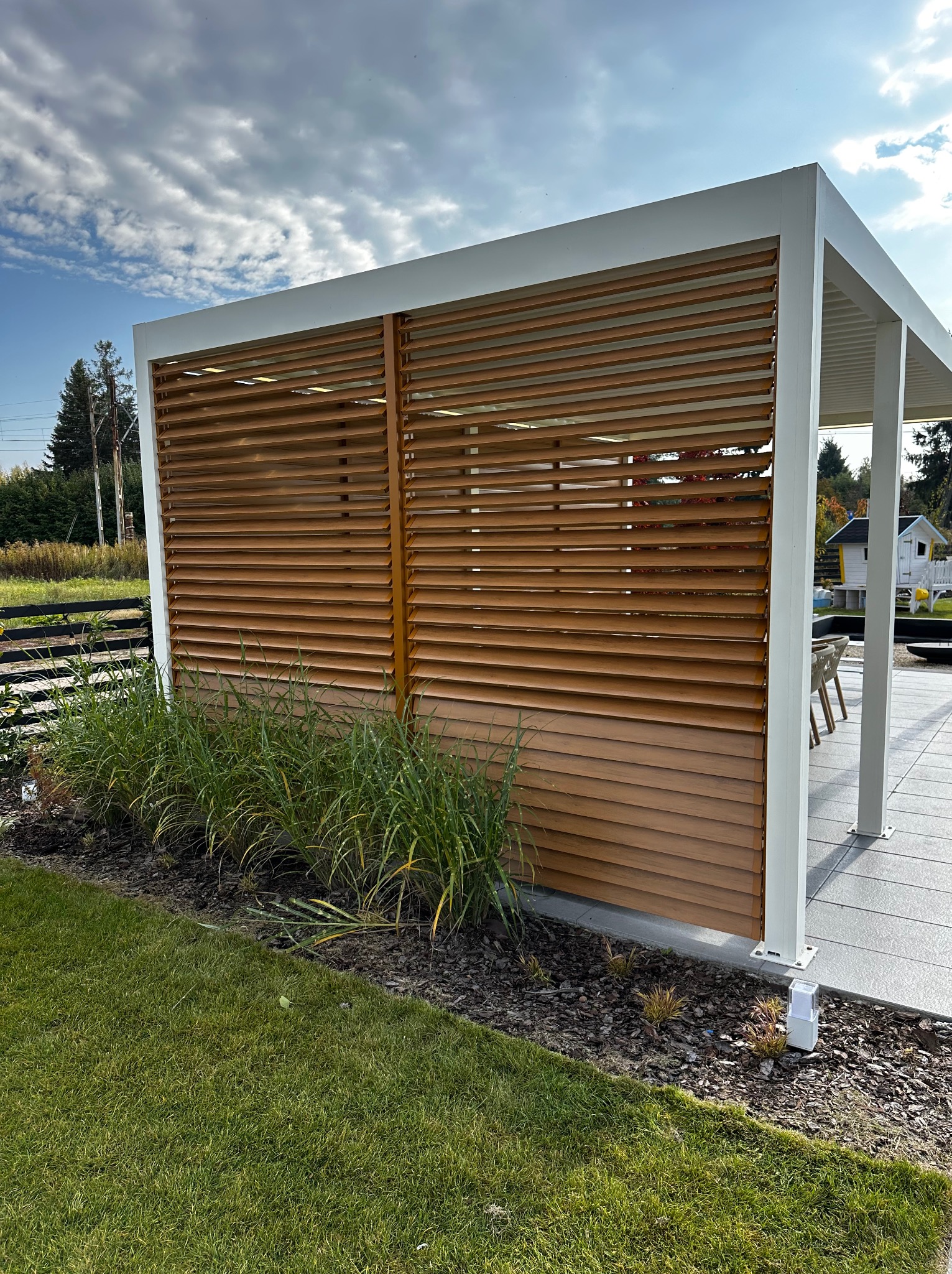 Pergola lamelowa oraz zabudowa boczna w formie obrotowych shuttersów poziomych