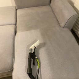 Justyna Symuś - Czyszczenie jasnoszarej sofy za pomocą ekstraktora z przezroczystą dyszą; widoczna różnica w odcieniu po czyszczeniu.