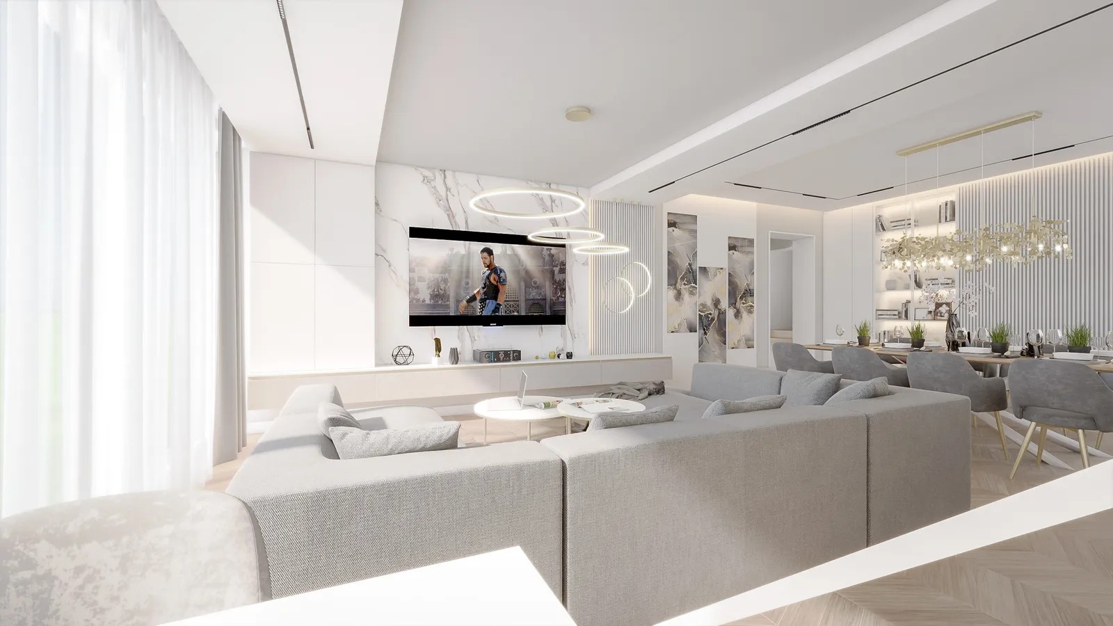 Jasne, przestronne wnętrze salonu z jadalnią, szary narożnik, telewizor na marmurowej ścianie, okrągłe lampy sufitowe i drewniana podłoga w jodełkę.