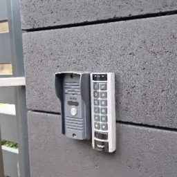 Szary wideodomofon Eura z klawiaturą Safet zamontowany na szarym, betonowym ogrodzeniu.