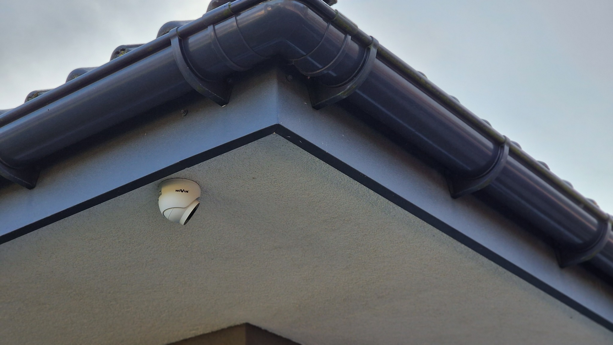 Kamera monitoringu marki Novus zamontowana pod okapem domu, widok z dołu.