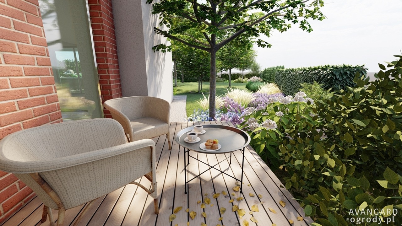Aranżacja tarasu z drewnianą podłogą, dwoma plecionymi fotelami, stolikiem z kawą i ciastkami, widok na zadbany ogród z kwitnącymi roślinami i strzyżonym żywopłotem.
