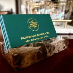 Wizytówki Kancelarii Adwokackiej adw. dr Patrycji Mieszkalskiej w eleganckim, marmurowym podajniku na biurku. Złoty nadruk na zielonym tle.