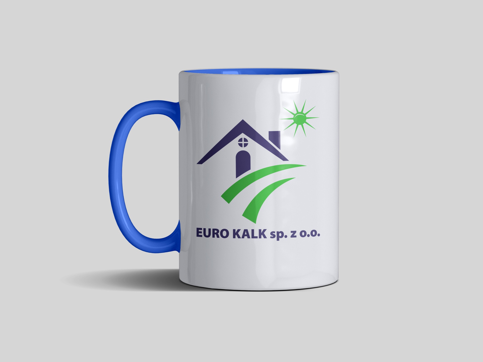 Biały kubek z niebieskim uchem i wnętrzem, nadrukowane logo firmy EURO KALK sp. z o.o. z motywem domu, słońca i zielonych pól.
