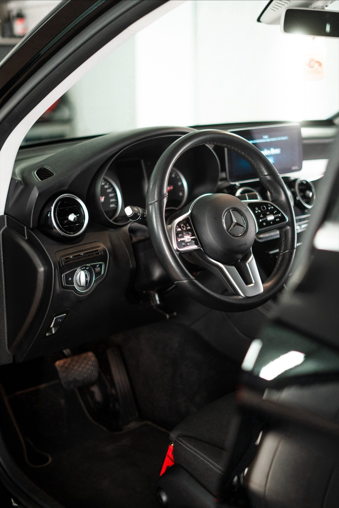 Wnętrze samochodu marki Mercedes-Benz z widoczną kierownicą, deską rozdzielczą i elementami wykończenia w czerni.