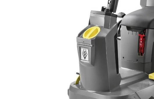 Fragment profesjonalnej maszyny czyszczącej z żółtym pokrętłem i symbolem trzech strzałek skierowanych w dół na szarej obudowie.