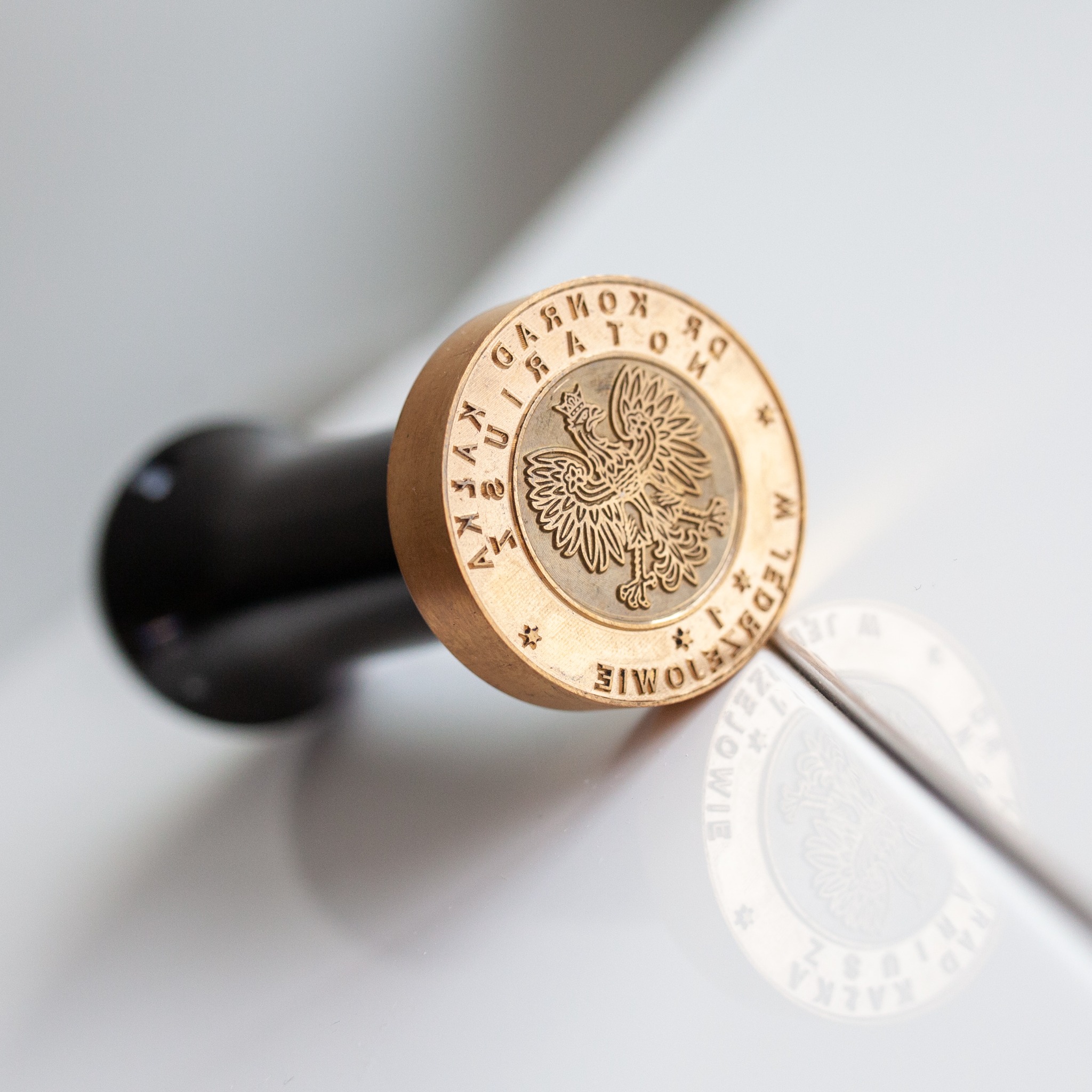 Mosiężna pieczęć z orłem w koronie i napisem 'Kancelaria Radcy Prawnego Iwona Kałka Mariusz Radzio'